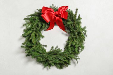 Beyaz arka planda kırmızı kurdeleli köknar dallarından yapılmış Noel çelengi