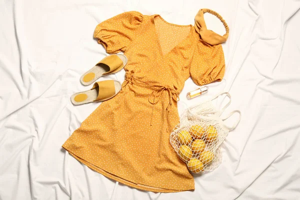 Düz kompozisyon, beyaz kumaş üzerinde şık sarı elbise.