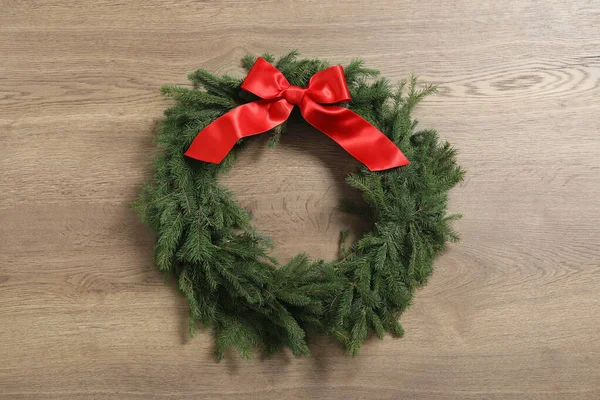 Noel çelengi köknar dallarından yapılmıştır. Ahşap arka planda kırmızı fiyonk vardır.