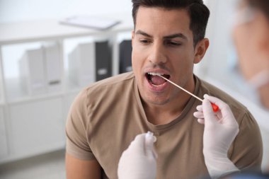 Doktor klinikteki adamdan DNA testi için örnek alıyor.