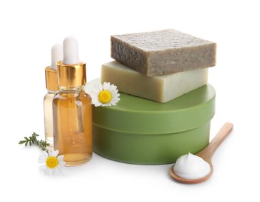 Beyaz arka planda farklı kozmetik ürünleri ve papatya çiçekleri.