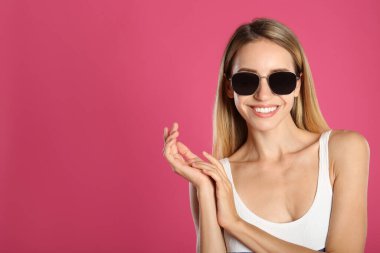 Pembe arka planda şık güneş gözlüklü güzel bir kadın. Metin için boşluk