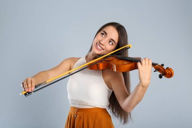 Gri arka planda keman çalan güzel kadın