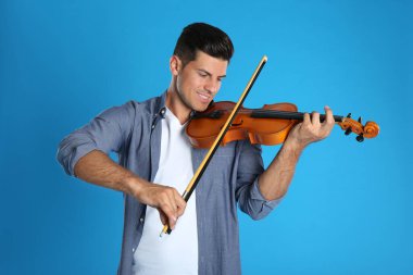 Açık mavi arka planda keman çalan mutlu adam