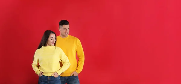 Pareja Feliz Usando Suéteres Cálidos Amarillos Sobre Fondo Rojo Espacio — Foto de Stock