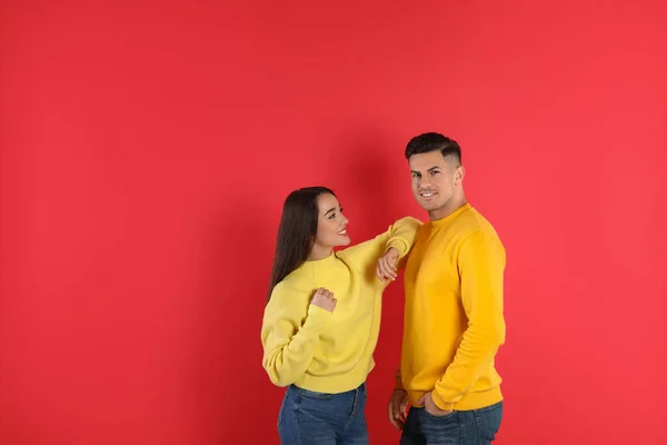 Pareja Feliz Vistiendo Suéteres Cálidos Amarillos Sobre Fondo Rojo — Foto de Stock