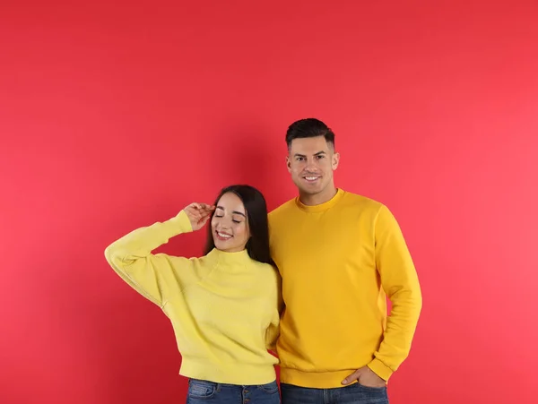 Pareja Feliz Vistiendo Suéteres Cálidos Amarillos Sobre Fondo Rojo — Foto de Stock