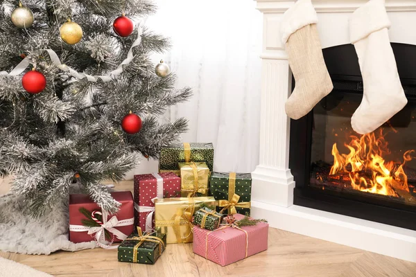 クリスマスツリーと暖炉の近くに多くの異なる贈り物室内 — ストック写真