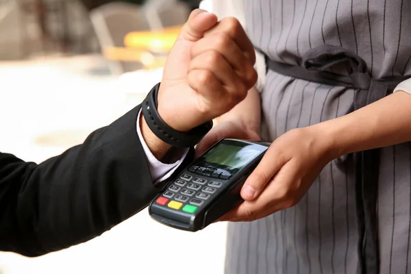 Man making payment with smart watch outdoors, closeup