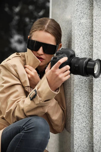 Private detective with modern camera spying on city street