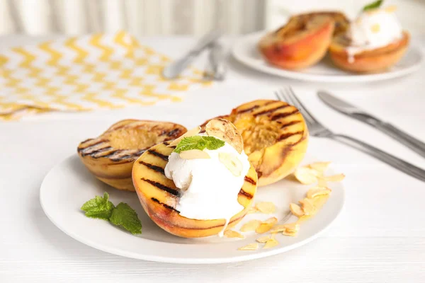 Delicious grilled peaches with ice cream served on white wooden table