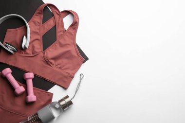 Açık gri arka planda spor kıyafetleri ve ekipmanlarla düz kompozisyon, metin için boşluk. Jimnastik