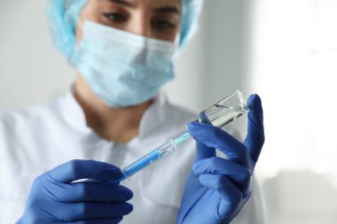 Klinikte şırıngayı ilaçla dolduran doktor, ellere odaklan. Aşılama ve aşılama