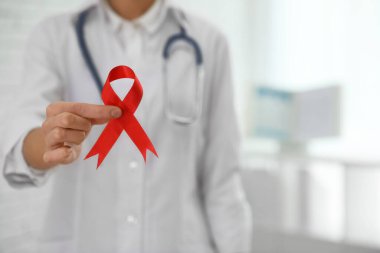 Arka planda kırmızı kurdele tutan bir doktor, mesaj için yeri olan bir doktor. AIDS Farkındalık Ayı