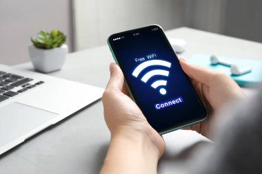 Wi-Fi 'a bağlanan kadın masadaki cep telefonunu kullanıyor, yakın plan