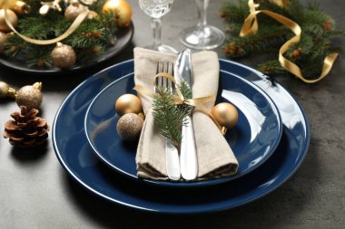 Gri arka planda güzel bulaşık takımları ve Noel dekoruyla şenlik masası.