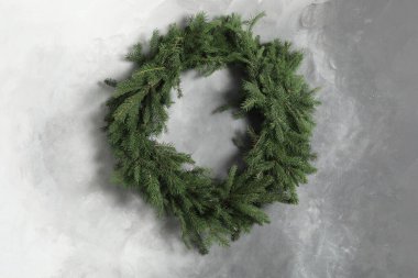 Gri duvardaki köknar dallarından yapılmış Noel çelengi