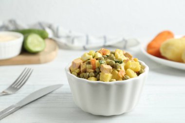 Lezzetli Rus salatası Olivier beyaz tahta masada servis ediliyor.