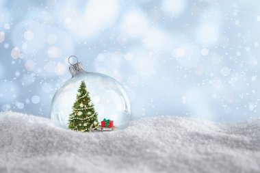 İçinde Noel ağacı olan güzel bir cam top ve açık mavi arka planda kara karşı hediye, mesaj için yer var. Bokeh etkisi