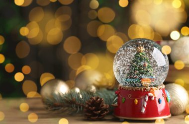 Güzel kar küresi ve ahşap masadaki Noel dekoru bulanık festival ışıklarına karşı, yazı için yer. Bokeh etkisi