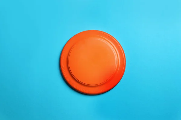 Disco Frisbee Plástico Naranja Sobre Fondo Azul Claro Vista Superior — Foto de Stock