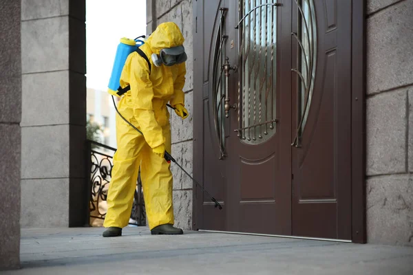 穿着防护服的人用喷雾器在门口消毒 大肠病毒大流行期间的表面治疗 — 图库照片