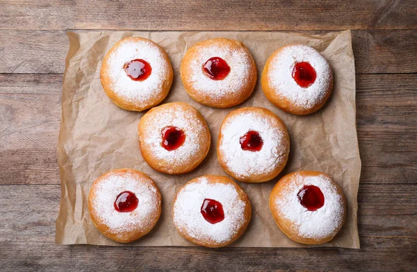 Hanukkah doughnuts with jelly and sugar powder on wooden table, flat lay