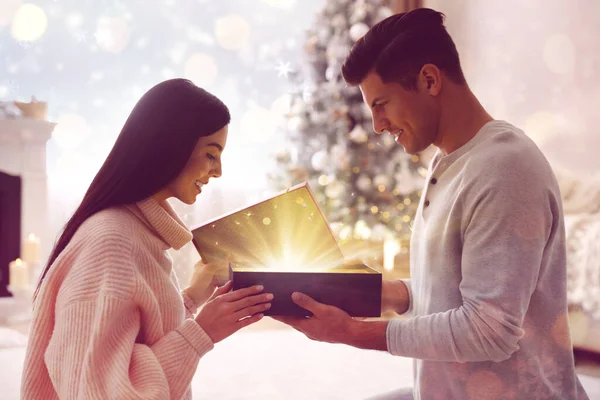 Couple Opening Christmas Gift Magic Light Home Bokeh Effect — Stock Photo, Image