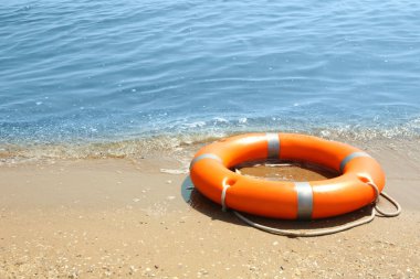 Denize yakın kumda turuncu yaşam şamandırası. Acil kurtarma ekipmanları