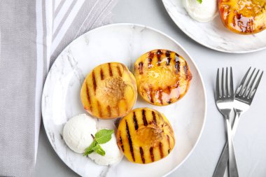 Lezzetli ızgara şeftali, dondurma ve bal. Gri masada, düz yerde.