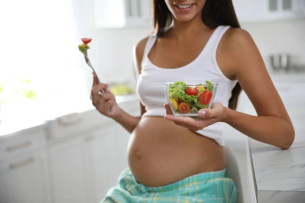 台所のテーブルで野菜サラダのボウルを持つ若い妊婦 クローズアップ 赤ちゃんの健康管理 — ストック写真