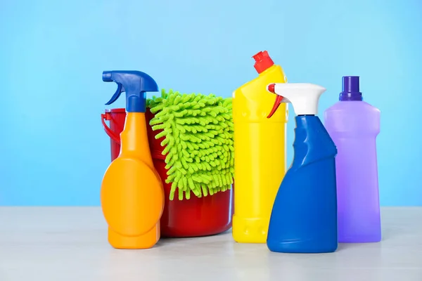 Bucket with different cleaning products and supplies on light table