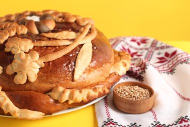 Sarı arka planda Korovai 'li Rushnyk, yakın plan. Ukrayna ekmek ve tuz karşılama geleneği