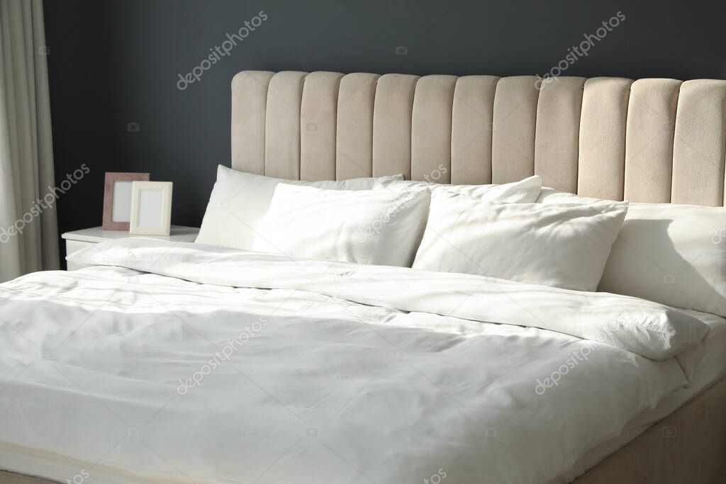 Comfortable bed with soft blanket and pillows indoors