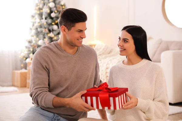 两人带着礼品盒和圣诞树在房间里 — 图库照片