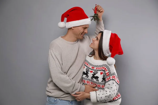 Noel Baba Şapkalı Mutlu Çift Gri Arka Planda Ökseotunun Altında — Stok fotoğraf