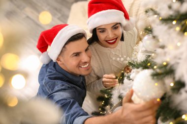 Mutlu çift evde Noel ağacı süslüyor, manzaranın üstünde.