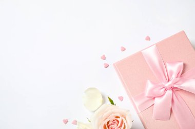 Pembe hediye kutusu ve beyaz arka planda güzel bir çiçek. Metin için boşluk