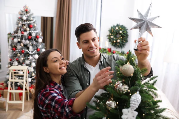 カップル飾るクリスマスツリーで星のトッパーで部屋 — ストック写真
