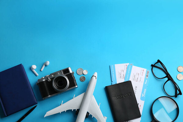 Flat lay composition with toy airplane and travel items on light blue background. Space for text