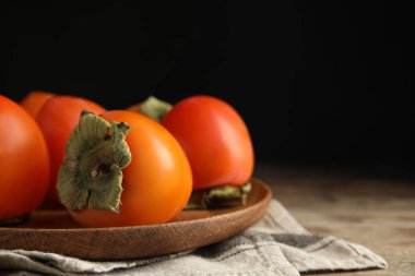 Tasty fresh ripe persimmons on table, closeup. Space for text