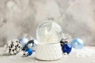 Güzel kar küresi, Noel topları ve ışık masasında çam kozalağı.