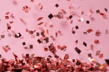 Pembe arka plana parlak bir konfeti düşüyor.