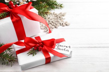 Gizli Noel Baba 'dan hediyeler ve beyaz ahşap masa üzerinde Noel dekorasyonu.