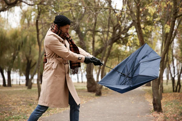 一个带着蓝色雨伞的人在室外被大风刮伤了 — 图库照片