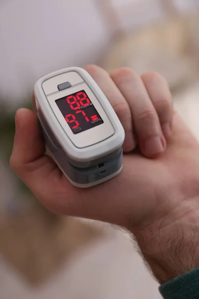 現代の指先パルス酸素濃度計で酸素濃度を測定する男屋内 クローズアップ — ストック写真