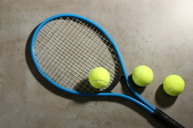 Tenis raketi ve toplar gri masada, düz yatıyordu. Spor malzemeleri.
