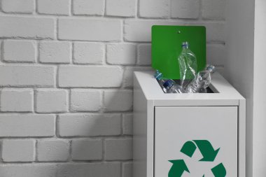 Çoğu beyaz tuğla duvarın yanındaki metal kutuda plastik şişe kullanıyordu. Geri dönüşüm sorunu