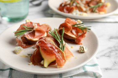 Lezzetli olgun incir ve prosciutto beyaz mermer masada servis edilir, yakın plan.