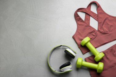 Spor kıyafetleri ve ekipmanlarla açık gri masada düz kompozisyon, yazı için boşluk. Jimnastik